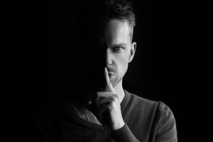 Become a Better Listener | jaconsulting.co.uk Man's face with finger to mouth to stay quiet